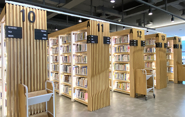 木質書架頂端加裝白色金屬條固定，兼具美感與防震效果。