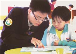 替代役男張志成陪著小朋友解釋圖書週題目。